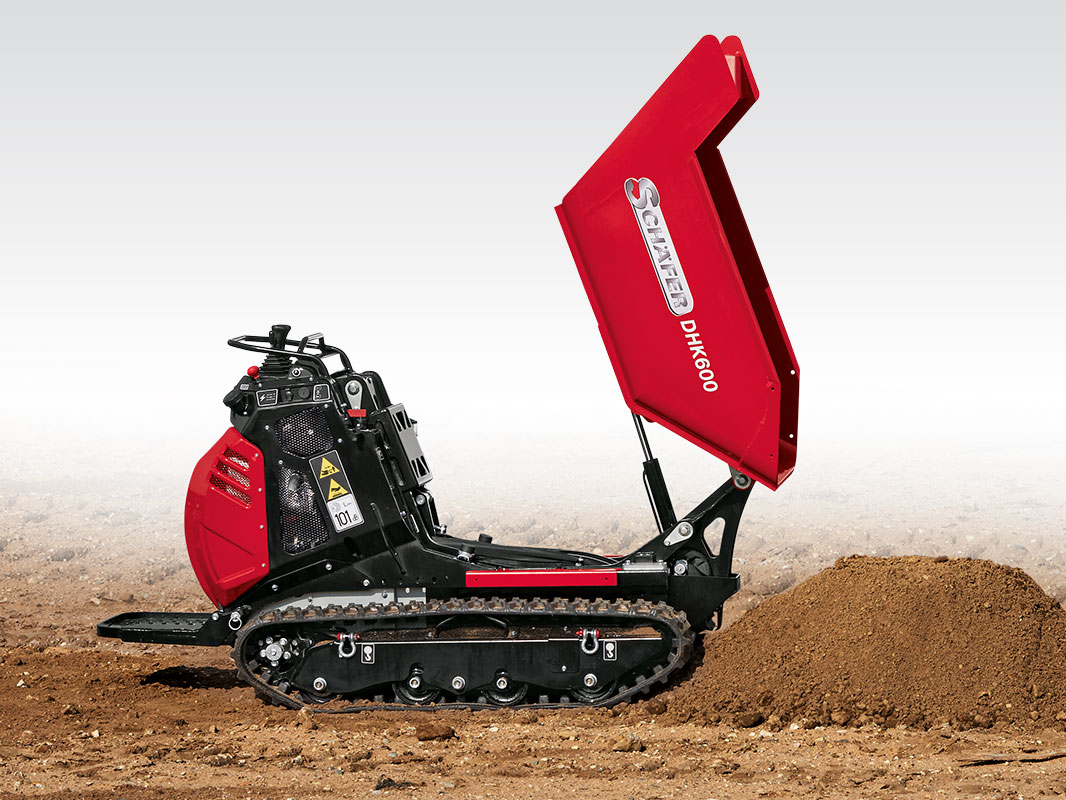 Dumper DHK 600 D mit gekippter Lademulde links neben einem niedrigen Erdhaufen